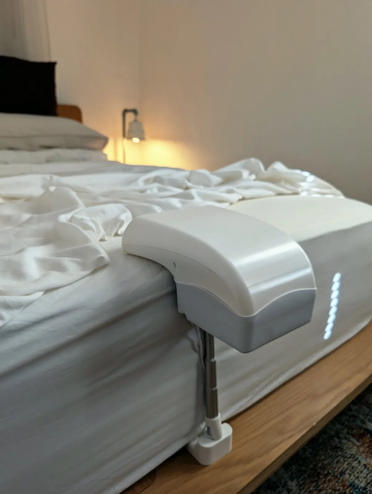 Close view of a single Fantail unit clamped to the side of a bed at night.